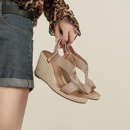 Paire de sandales compensées Alba dorées tenue à la main