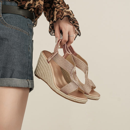 Paire de sandales compensées Alba dorées tenue à la main